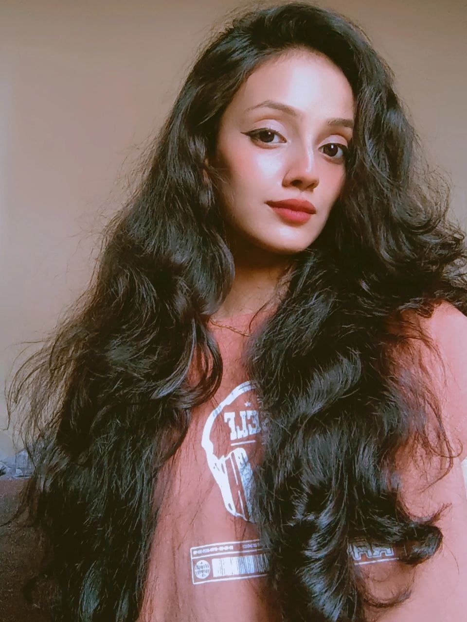 Portrait of Riya Sharma, mid-conversation, against a deep teal backdrop